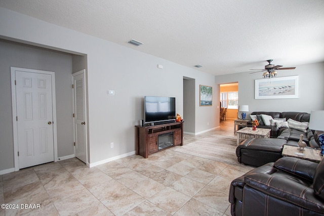 living room featuring ceiling fan and a textured ceiling