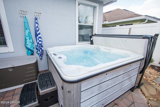 view of patio / terrace featuring a hot tub and fence