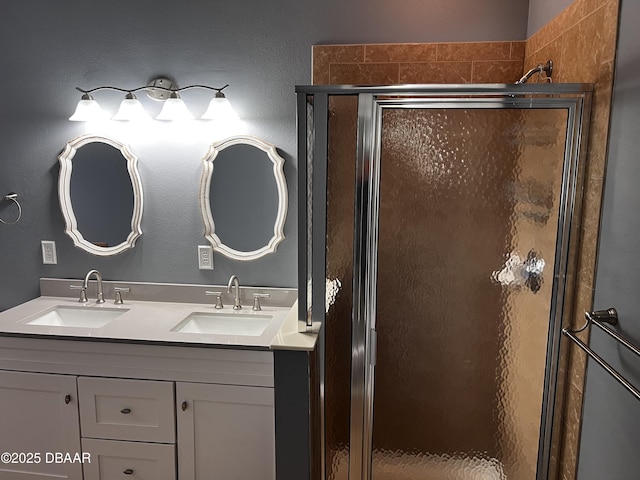 bathroom featuring double vanity, a shower stall, a sink, and a textured wall