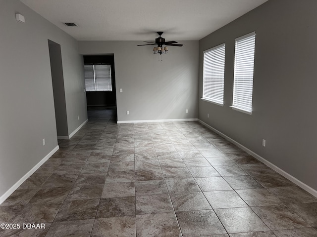 spare room with ceiling fan, visible vents, and baseboards