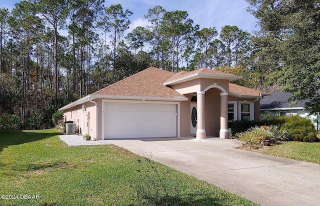 view of front of house with central AC unit, a garage, and a front lawn