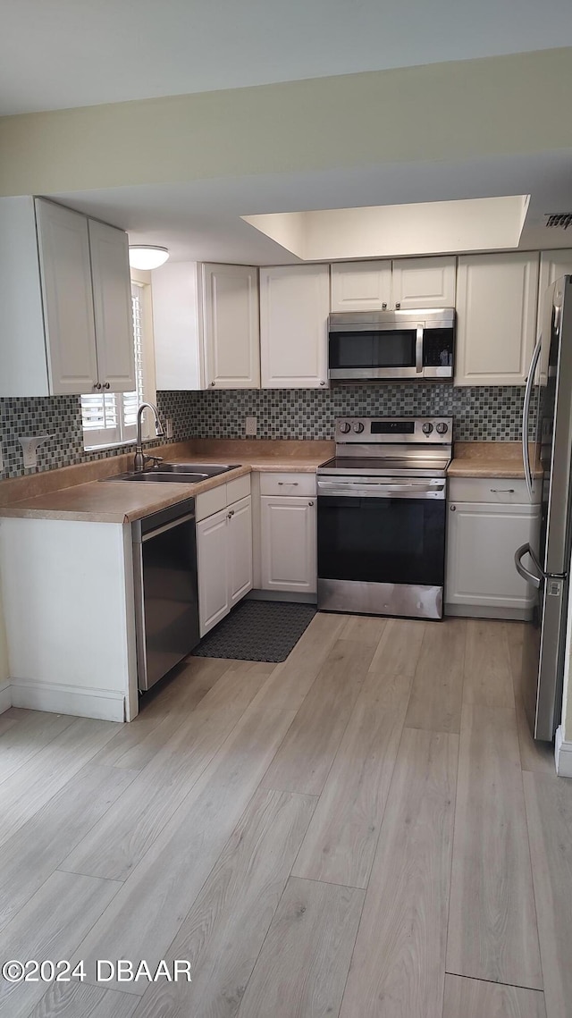 kitchen featuring white cabinets, light wood-type flooring, appliances with stainless steel finishes, and sink