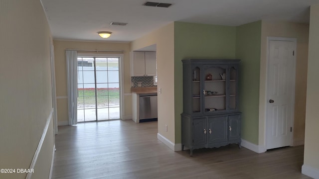 interior space featuring light wood-type flooring, decorative backsplash, and dishwasher