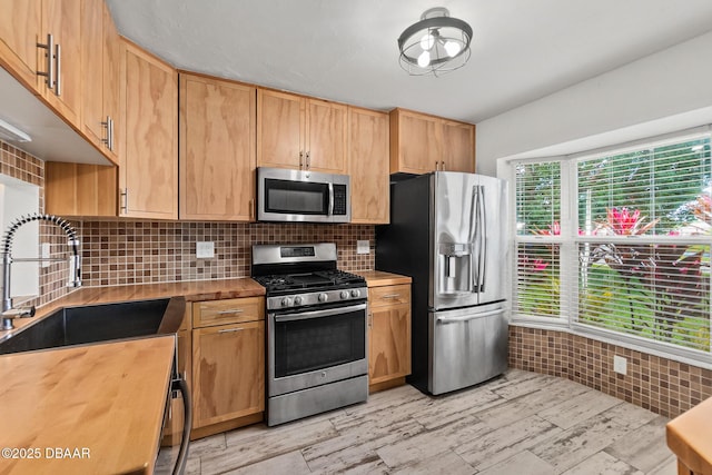 156 S Woodbridge Cir, Daytona Beach, FL 32119 - kitchen with appliances with stainless steel finishes, a sink, wood counters, decorative backsplash, and light wood-style flooring
