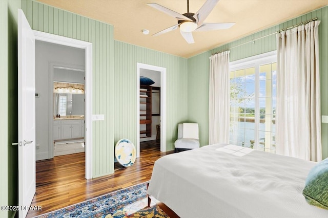 bedroom with a closet, wood finished floors, a spacious closet, and wallpapered walls