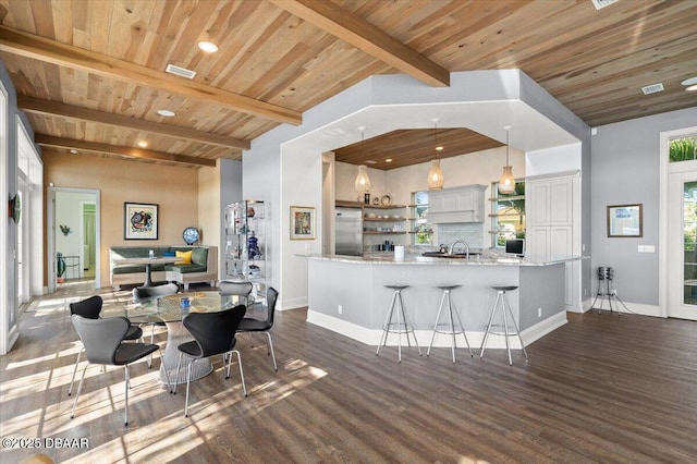 kitchen with backsplash, beamed ceiling, stainless steel built in fridge, light stone counters, and wooden ceiling