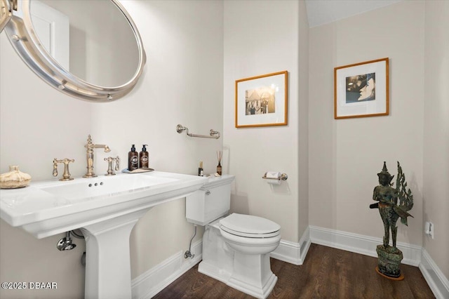 bathroom featuring toilet, wood finished floors, baseboards, and a sink