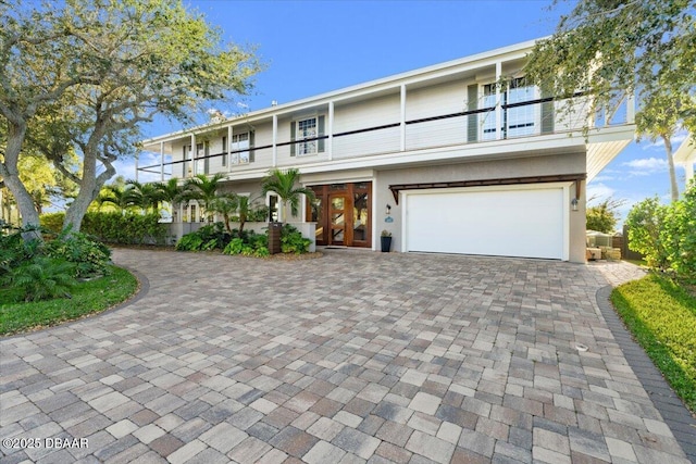 view of front facade with decorative driveway, a balcony, and an attached garage