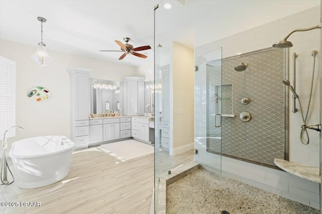 full bath featuring a stall shower, wood finished floors, a soaking tub, ceiling fan, and vanity