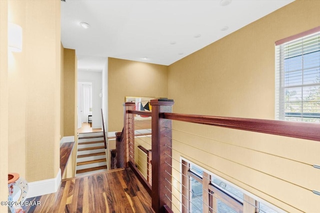 hallway with wood finished floors, an upstairs landing, and baseboards