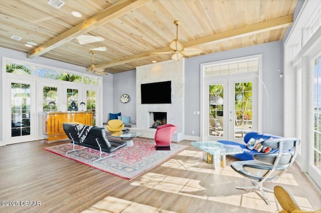 living room with a wealth of natural light, french doors, beam ceiling, and a fireplace