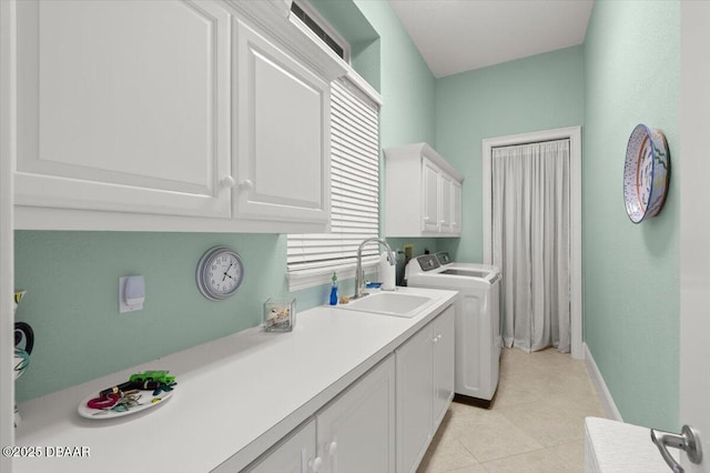 clothes washing area featuring a sink, cabinet space, light tile patterned floors, baseboards, and washing machine and clothes dryer