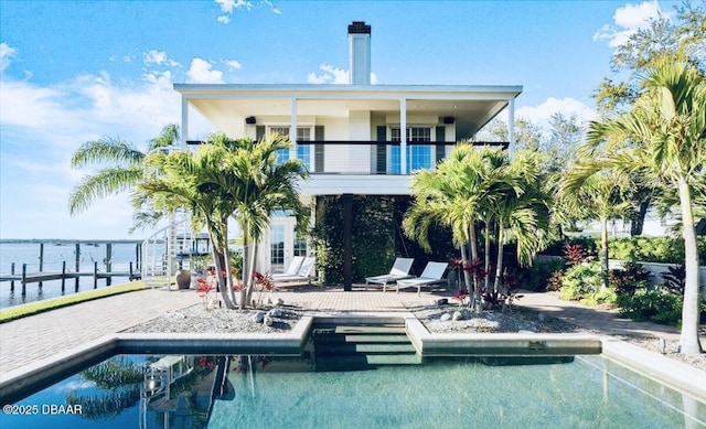 rear view of house with a patio, a balcony, and an outdoor pool