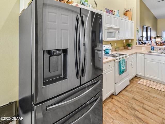 kitchen with white cabinets, light countertops, white appliances, and a sink