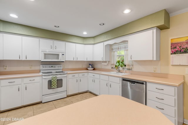 kitchen with sink, light tile patterned floors, white appliances, white cabinets, and ornamental molding