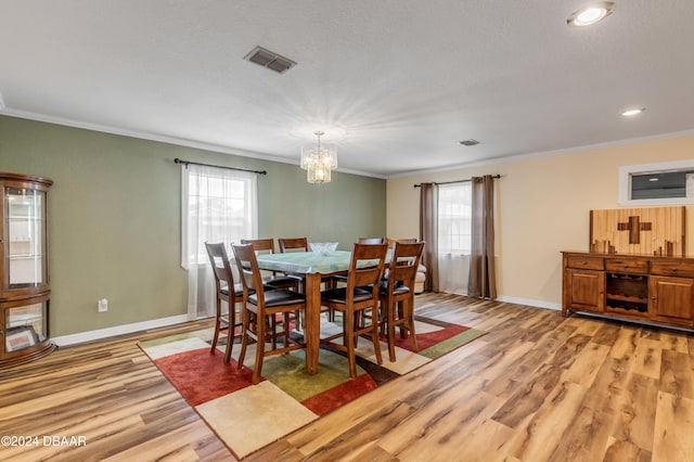 dining area featuring crown molding, a healthy amount of sunlight, and light hardwood / wood-style floors