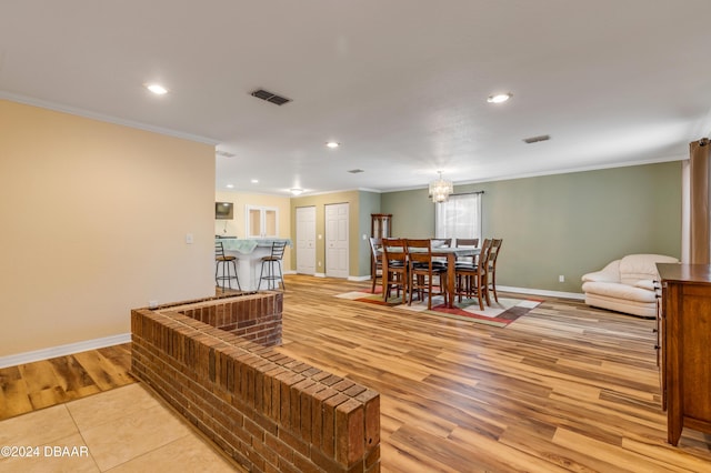 living room featuring light wood-type flooring, crown molding, and a notable chandelier