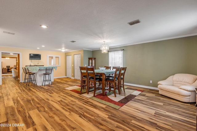 dining room with crown molding, light hardwood / wood-style floors, and a notable chandelier