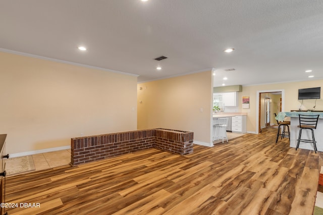 empty room with crown molding, light hardwood / wood-style flooring, and a textured ceiling