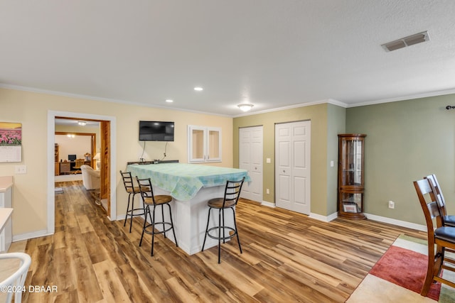 kitchen with light hardwood / wood-style flooring, a breakfast bar area, and crown molding