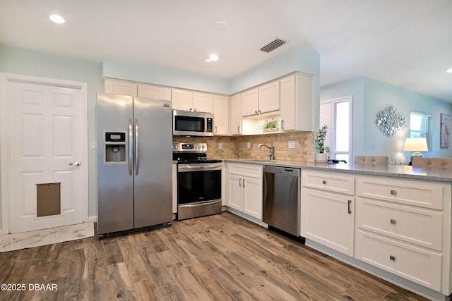 22 Sand Dune Dr, New Smyrna Beach, FL 32169 - kitchen featuring appliances with stainless steel finishes, white cabinets, backsplash, dark wood finished floors, and recessed lighting