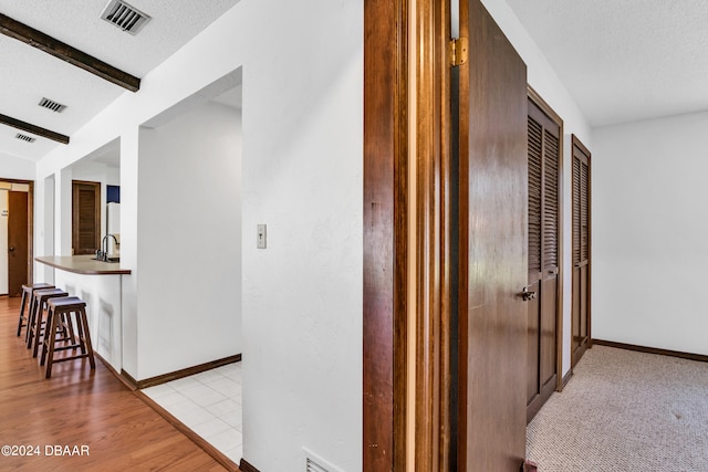 75 Sycamore Cir, Ormond Beach, FL 32174 - corridor with beamed ceiling, a textured ceiling, and light hardwood / wood-style floors