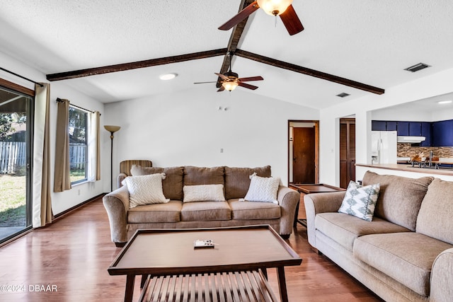 75 Sycamore Cir, Ormond Beach, FL 32174 - living room featuring ceiling fan, wood-type flooring, a textured ceiling, and vaulted ceiling with beams