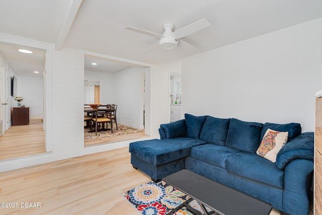 living room featuring ceiling fan, hardwood / wood-style flooring, and beamed ceiling