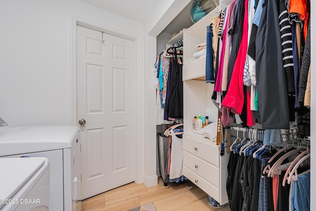 spacious closet featuring washer and clothes dryer and light hardwood / wood-style floors