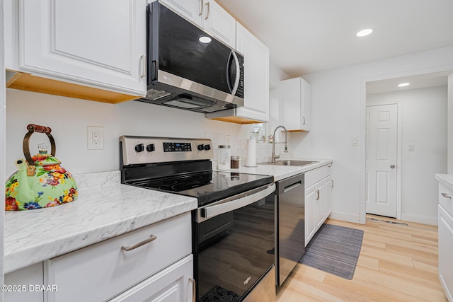 kitchen with light hardwood / wood-style floors, sink, stainless steel appliances, and white cabinetry