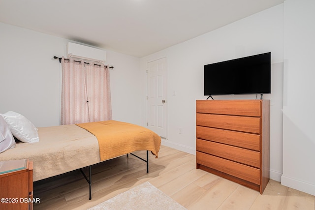 bedroom featuring a wall unit AC and light wood-type flooring