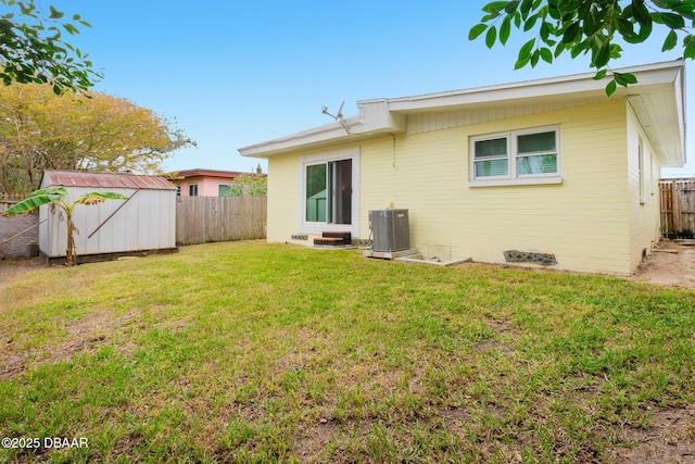 rear view of property with central AC unit, a yard, and a storage shed