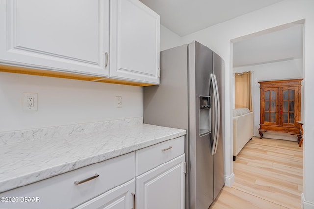 kitchen with light hardwood / wood-style floors, light stone countertops, white cabinetry, and stainless steel fridge with ice dispenser