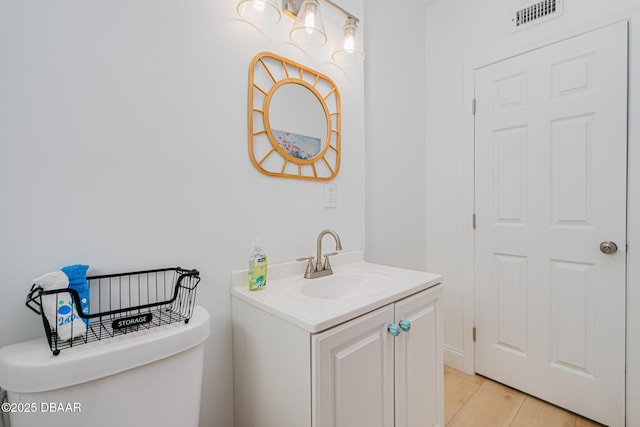 bathroom featuring toilet, vanity, and hardwood / wood-style flooring