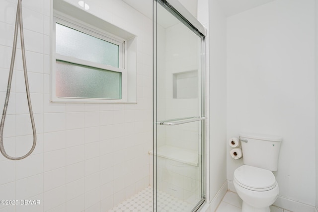 bathroom featuring a shower with shower door and toilet