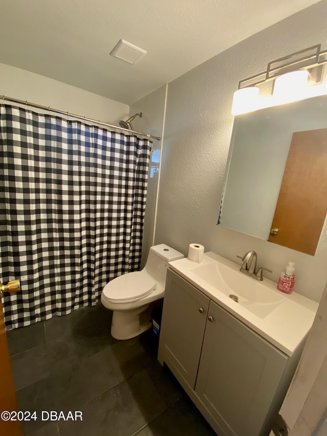 bathroom with tile patterned flooring, vanity, toilet, and a textured ceiling