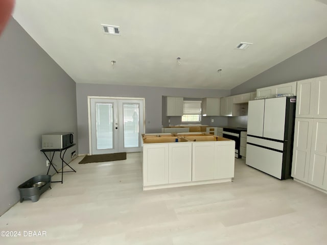 kitchen with french doors, vaulted ceiling, dishwashing machine, white fridge, and white cabinetry