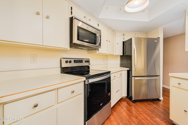 kitchen featuring a raised ceiling, white cabinetry, dark hardwood / wood-style floors, and appliances with stainless steel finishes