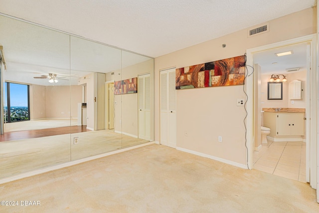 carpeted spare room with ceiling fan, sink, and a textured ceiling