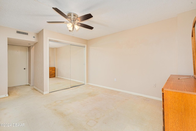 unfurnished bedroom with carpet flooring, ceiling fan, a closet, and a textured ceiling