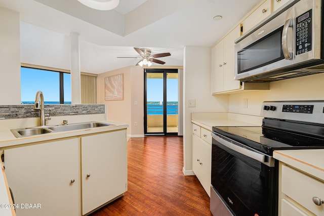 kitchen with appliances with stainless steel finishes, sink, a water view, white cabinets, and dark hardwood / wood-style floors