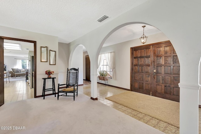 carpeted entryway featuring a wealth of natural light and a textured ceiling