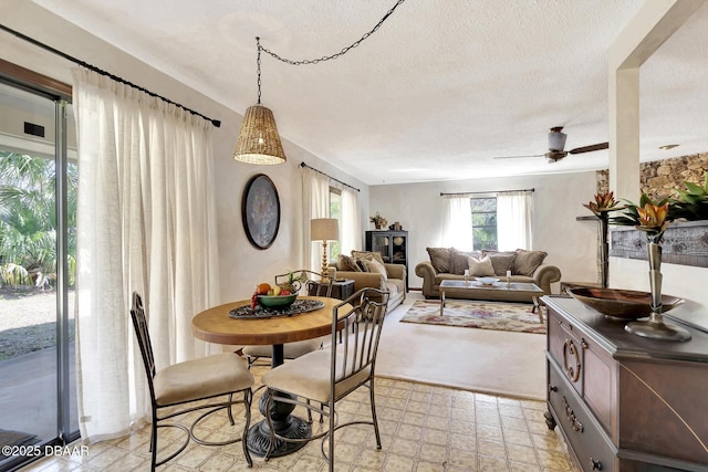 dining space featuring ceiling fan and a textured ceiling