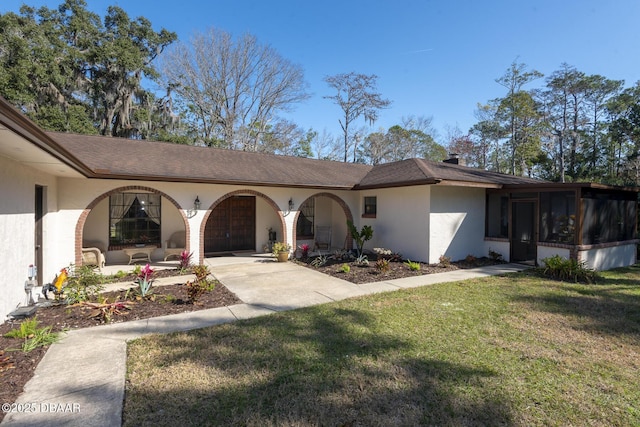 ranch-style home with a sunroom, a front lawn, and a garage