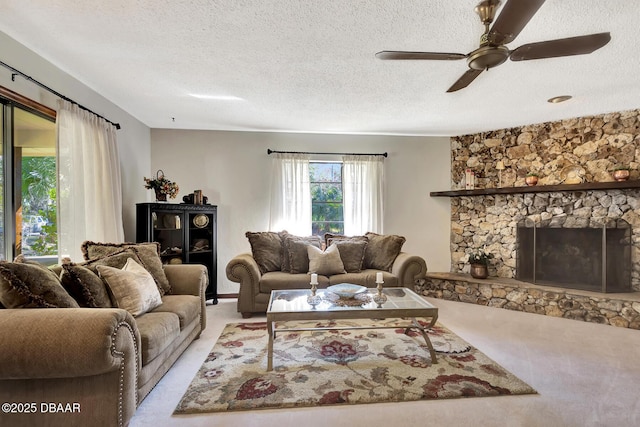 living room with ceiling fan, light carpet, a textured ceiling, and a fireplace