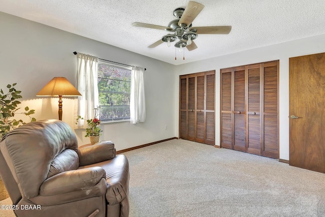 living area featuring ceiling fan, light carpet, and a textured ceiling