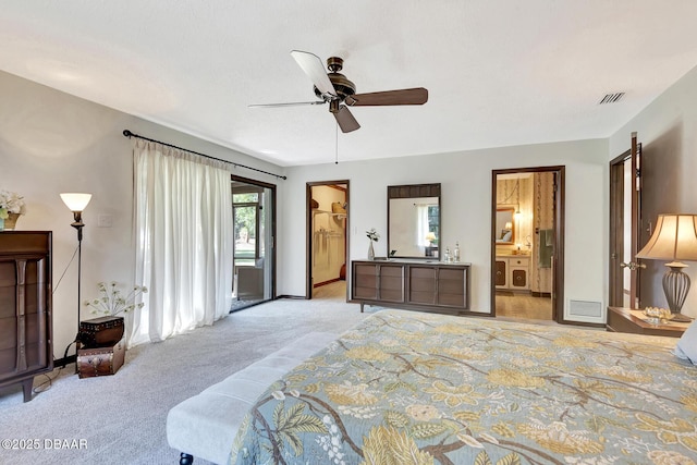 carpeted bedroom with a walk in closet, ceiling fan, and ensuite bath