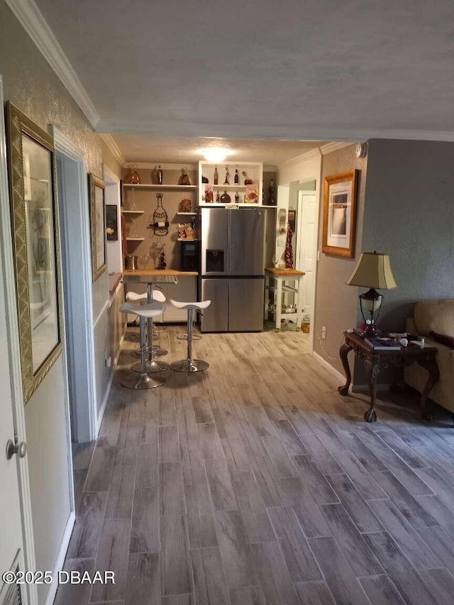 kitchen with stainless steel refrigerator with ice dispenser, hardwood / wood-style floors, and ornamental molding