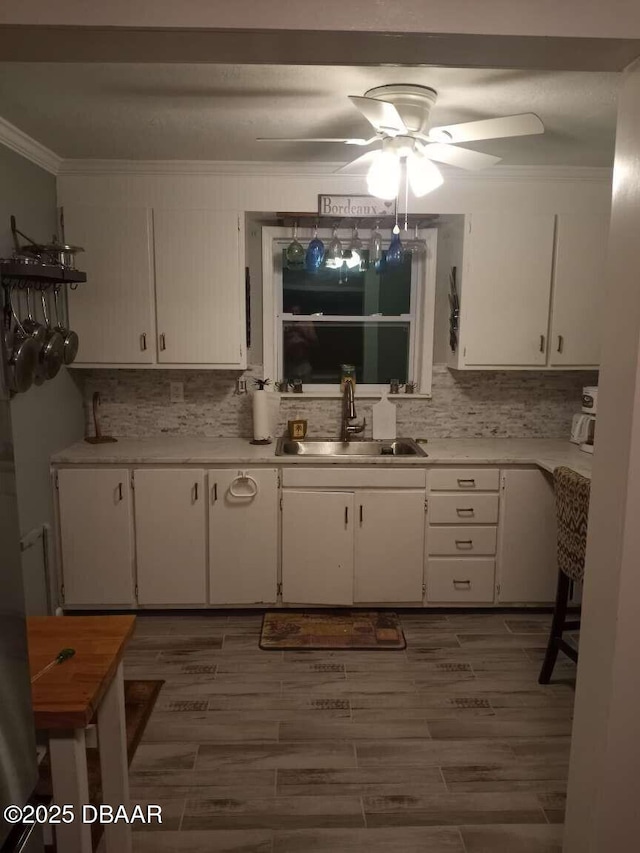 kitchen featuring white cabinets, dark hardwood / wood-style flooring, ornamental molding, ceiling fan, and sink