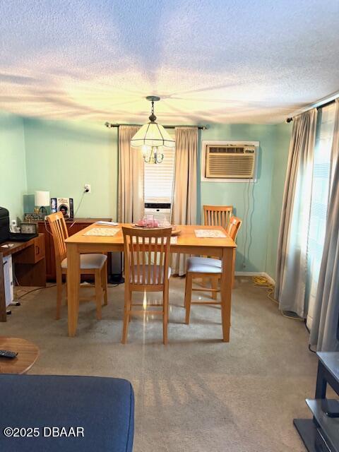 dining space featuring an inviting chandelier, carpet floors, an AC wall unit, and a textured ceiling